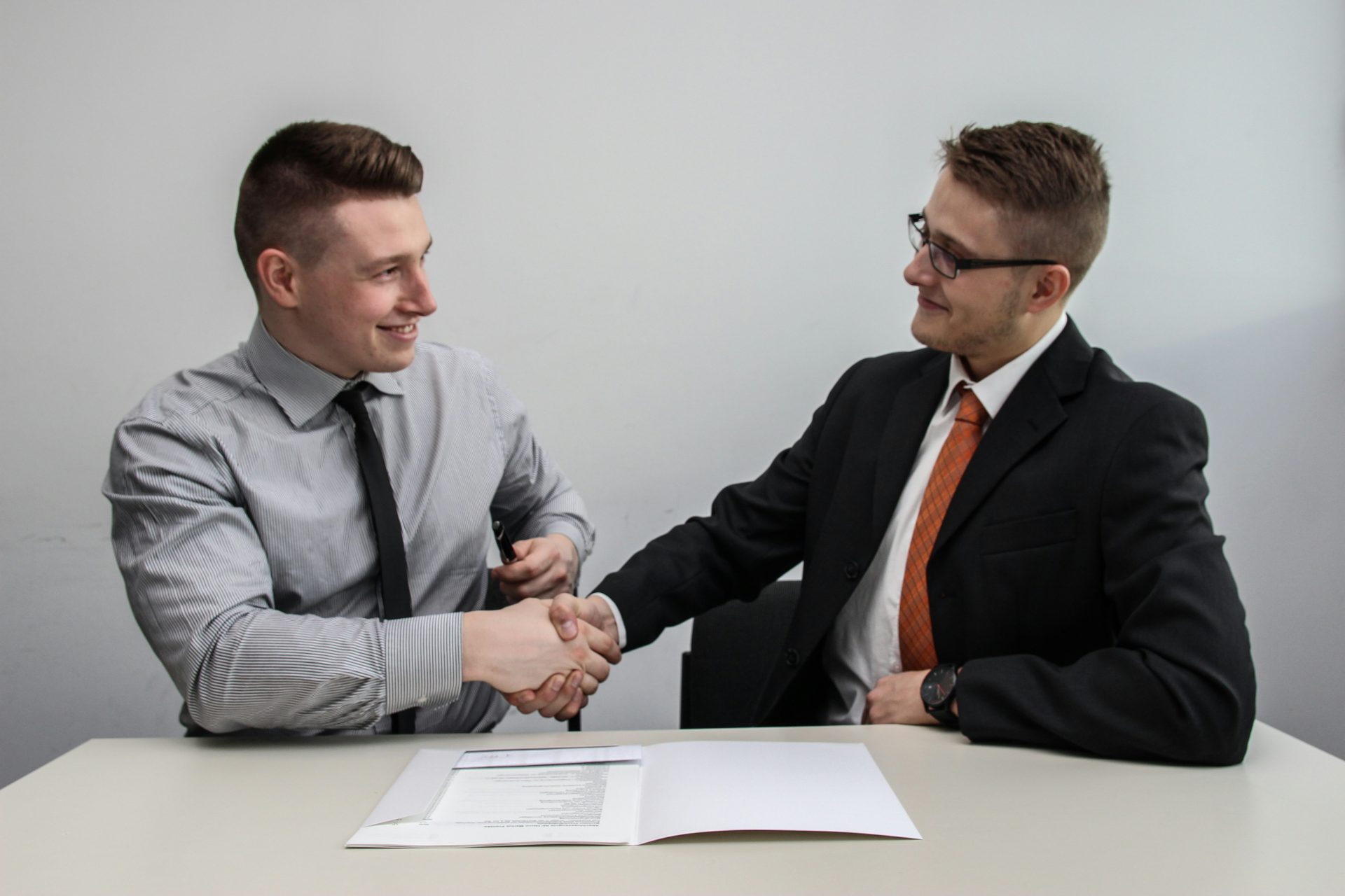 Two businessmen shaking hands over contract.